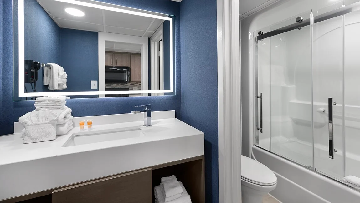A clean bathroom with a white sink, large mirror, and glass shower door