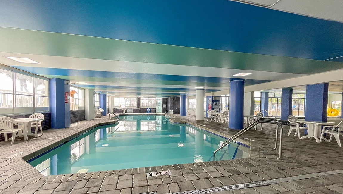 An indoor pool with a blue ceiling and gray tile floor