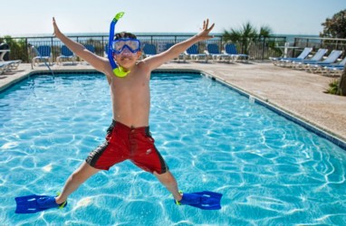 Boy jumping by the outdoor pool